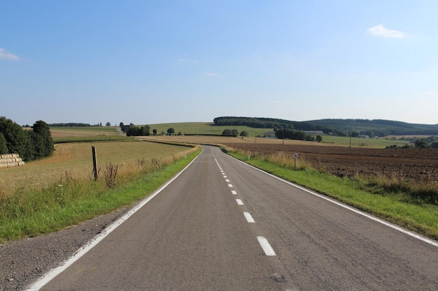 Leeg weg op landbouwveld tegen de lucht