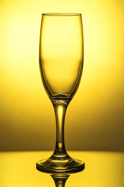 Foto leeg wijnglas met reflectie, op het dakraam, op een gele achtergrond met een gradiëntvlek
