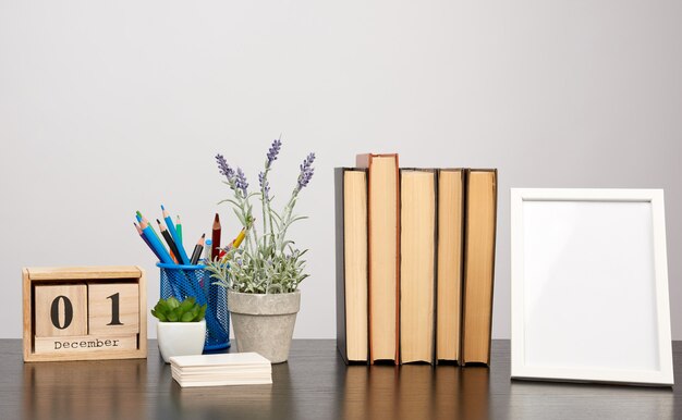 Leeg wit fotokader, stapel boeken en een pot met groeiende lavendel op een zwarte tafel