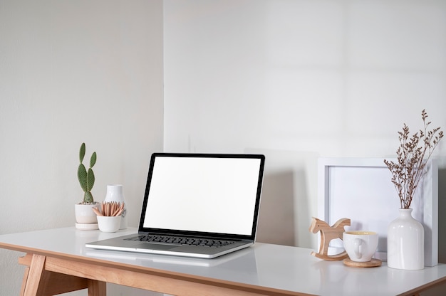 Leeg wit scherm laptopcomputer en decoratie objecten op houten tafel, creatief werkruimte concept.