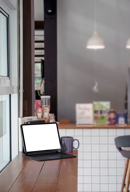 Leeg wit scherm tablet met magisch toetsenbord op houten aanrechttafel in café kamer, verticale weergave.