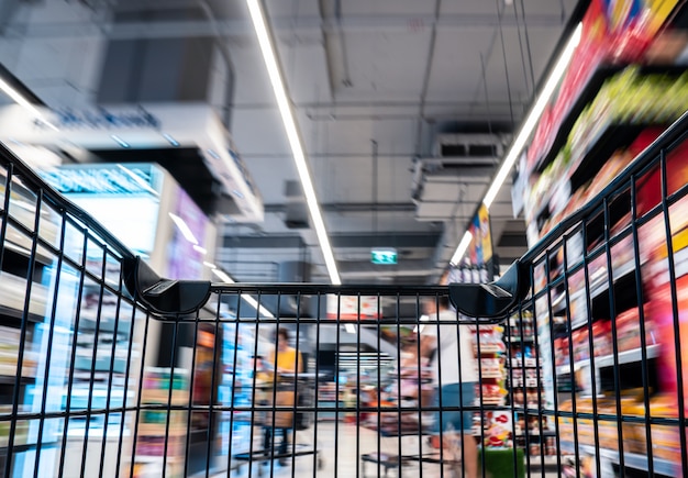 Leeg zwart boodschappenwagentje met motie in de supermarktdoorgang verplaatsen