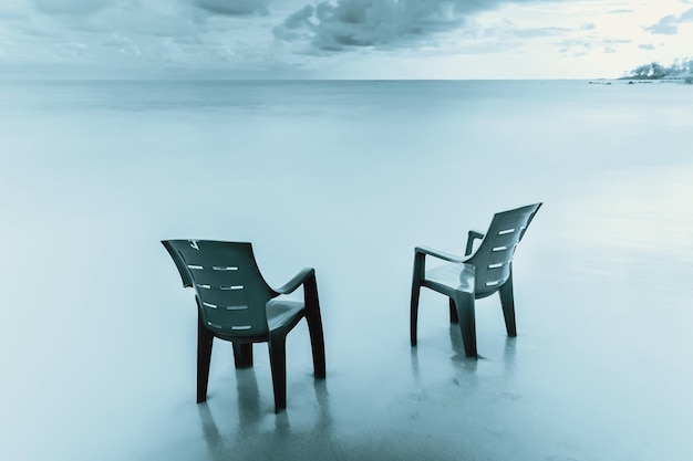 Leegte stoelen en tafel bij de zee tegen de lucht