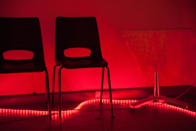 Foto leegte stoelen tegen een verlichte muur.