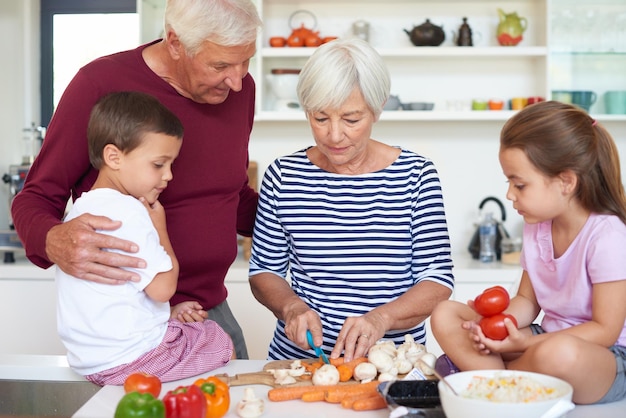 Leer de fijne kneepjes van het koken Shot van grootouders die het diner met hun kleinkinderen in een keuken bereiden