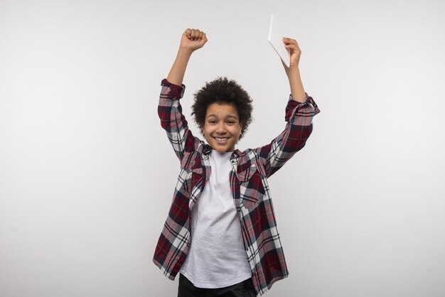 Leerling van de school. Aardige slimme jongen die zijn handen omhoog houdt terwijl hij blij is met het winnen van de schoolwedstrijd