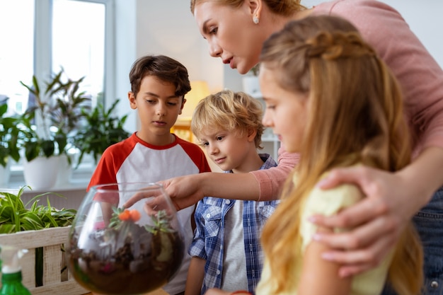 Leerlingen helpen. Blondharige jonge ecologieleraar helpt haar leerlingen over planten en bloemen