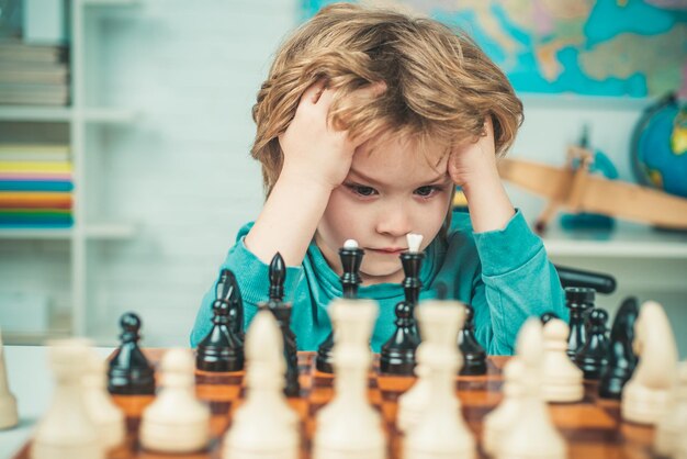 Leerlingjongen die nadenkt over zijn volgende zet in een schaakspel Slim geconcentreerd en denkend kind dat