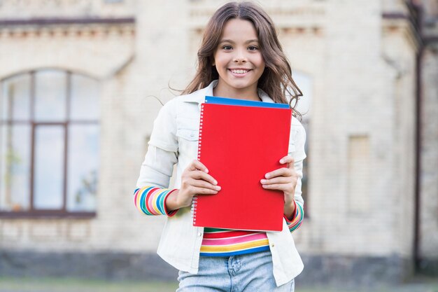 Lees meer boeken. Gelukkig klein kind dat naar de bibliotheek gaat om boeken te nemen. Aanbiddelijk meisje dat op de basisschool leert lezen. Ik zal overal lezen.