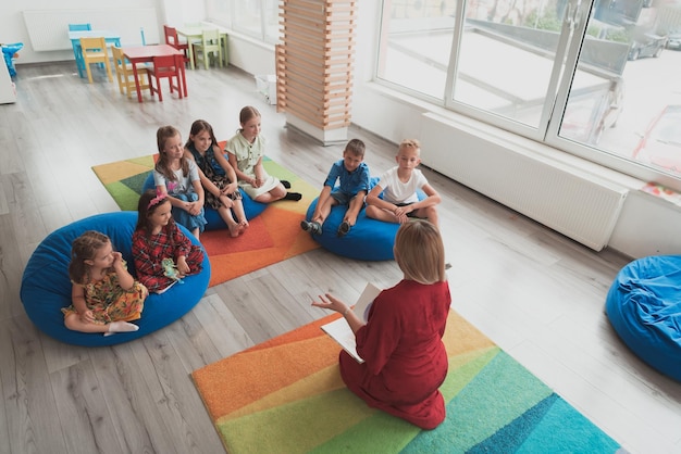 Leestijd op een basisschool of kleuterschool een leraar leest een boek voor aan kinderen op een basisschool of kleuterschool Het concept van voorschoolse educatie Selectieve focus