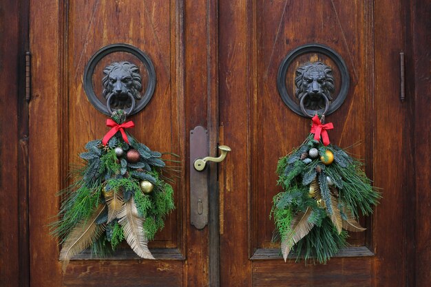 Leeuwenkop bronzen deurkloppers versierd met kerstkransen. kerstkransen op houten deuren