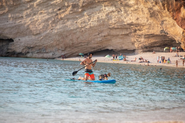 Lefkada Greece September 7 2021 man paddle boarding with dog sea vacation