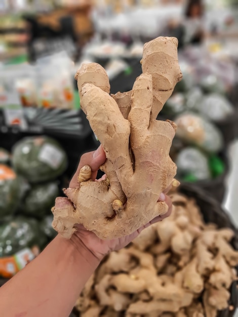 Left hand holding ginger, ginger for sale in the supermarket.