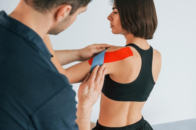 On the left hand Woman visiting physiologist that putting kinesio tape on the skin