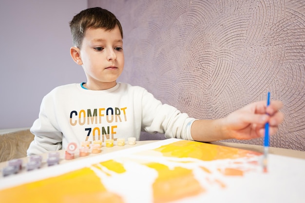 Left handed boy is painting by numbers with gouache at home Comfort zone