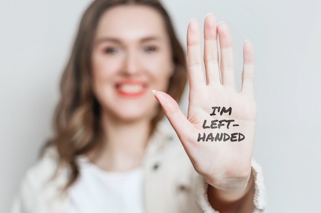 Photo left-handed girl shows her left-hand smiles isolated over grey background