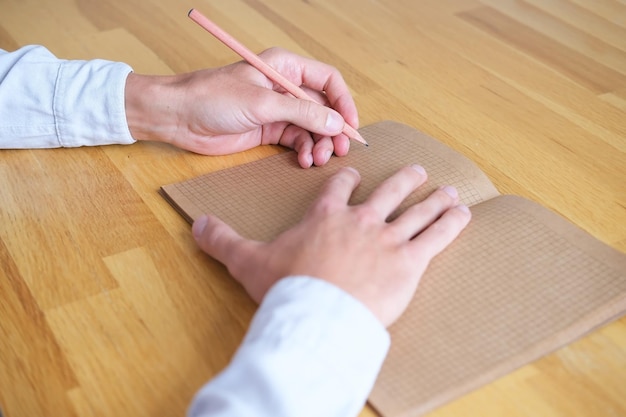 Left-handed person writing on kraft paper note