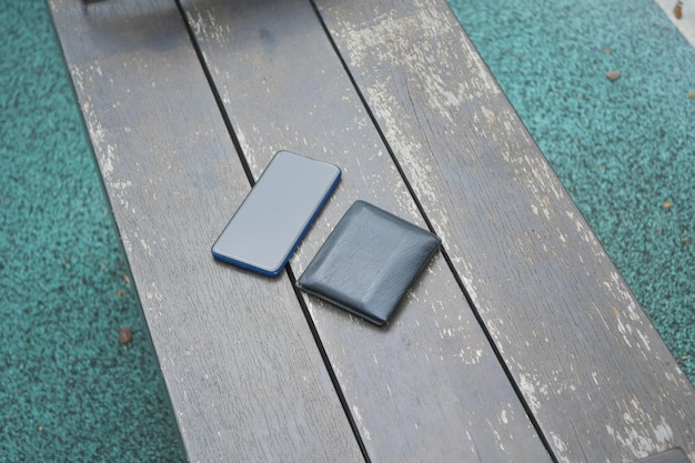 Left wallet and smart phone on a bench in the park