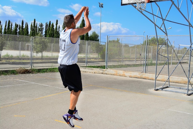 Giocatore di basket mancino che spara in un parco giochi