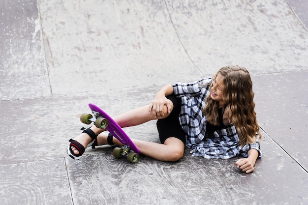 Foto lesioni alle gambe e alle ginocchia su penny board traumatologia infantile bambina che cade dallo skate board e si ferisce e sente dolore