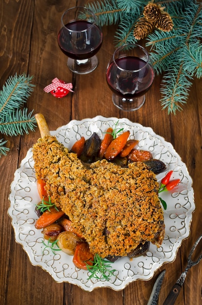Photo leg of lamb baked with spicy bread crust. roast leg of lamb with roasted vegetables in the round dish