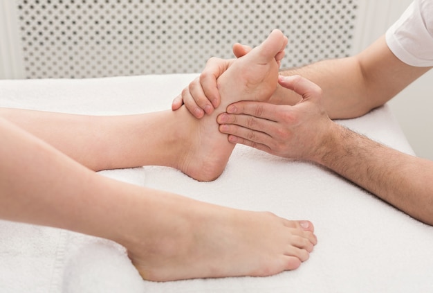 Leg massage. Physiotherapist pressing specific spots on female foot. Professional health and wellness acupressure manipulations, copy space, closeup