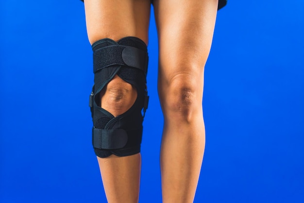 Photo a leg with knee support brace over a blue background recovering concept