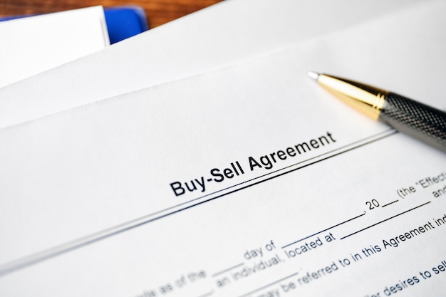 Legal document Buy-Sell Agreement on paper with pen.