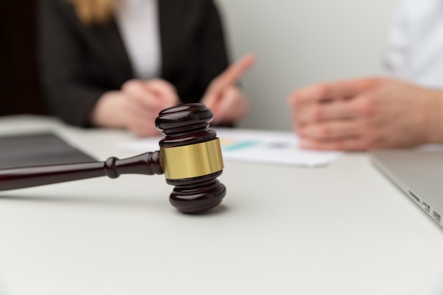 Legal support concept. People sitting at the desk with wooden hammer on it.