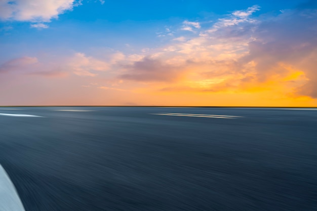 Lege asfaltweg en natuurlijk landschap in de ondergaande zon