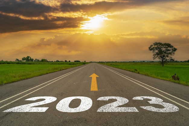 Lege asfaltweg en Nieuwjaar 2023 concept Rijden op een lege weg naar Goals 2023 met zonsondergang