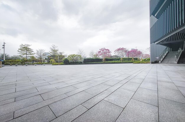 Lege bakstenen pleinen en moderne gebouwen in stadsparken met groene boomachtergrond