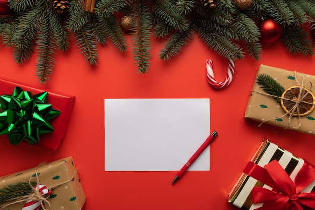 Foto lege brief op rode achtergrond met geschenken en kerstversiering