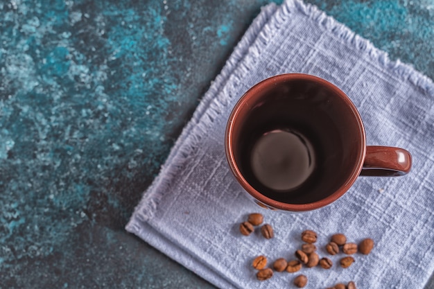 Lege bruine mok voor koffie en koffiebonen op blauwe achtergrond