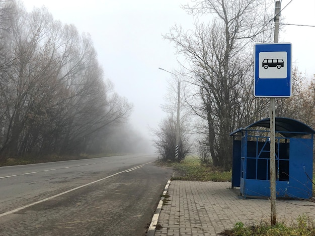 Lege bushalte aan de zijkant van de asfaltweg in mistige herfstochtend