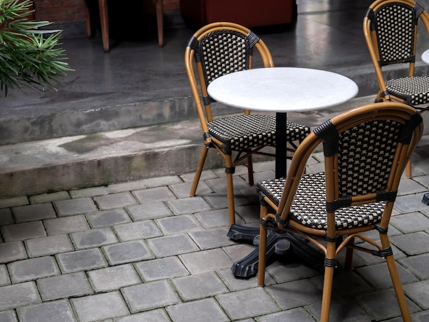 Lege comfortabele vintage rotan stoelen met ronde marmeren tafel gedecoreerd op grijze betonnen bakstenen tegelvloer in het natuurlijke schemerige gebouw met kopieerruimte Gezellig woongedeelte interieur