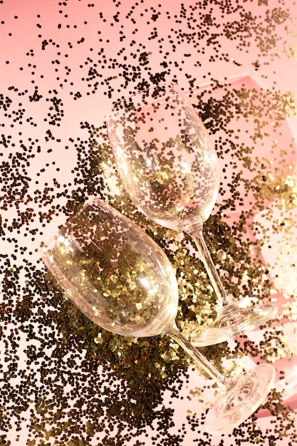 Lege glazen bekers voor champagne in gouden confetti op tafel. feestelijke achtergrond. partijconcept.