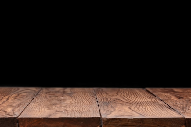 Lege houten dektafel tegen zwart behang voor huidig product en andere dingen.