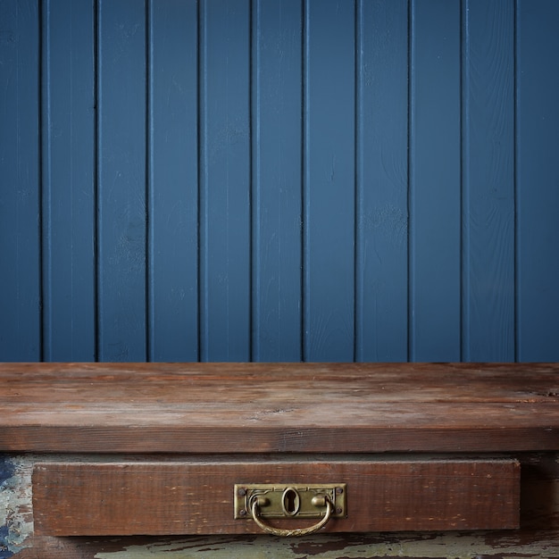 Lege houten tafel tegen een muur van de planken geschilderd in blauwe kleur.