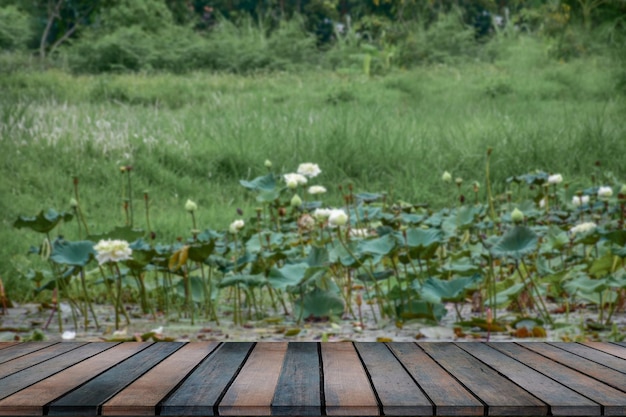 Lege houten tafel voor een plas water. Onscherpe achtergrond met lotusbloemen.