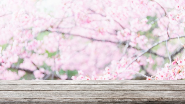 Lege houten tafelblad en wazig sakura bloem boom op tuin achtergrond.