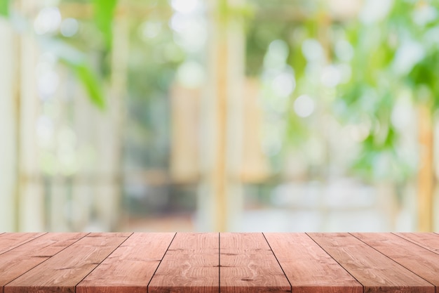 Lege houten tafelblad en wazig van interieur kamer met raam uitzicht van groene boom tuin achtergrond achtergrond.