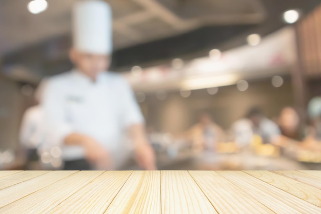 Lege houten tafelblad met chef-kok koken in restaurant keuken wazig intreepupil achtergrond