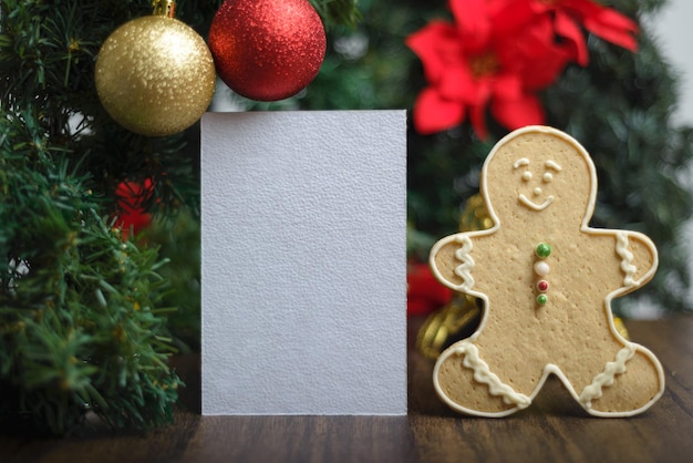 Lege kaart naast peperkoek man cookie en ornamenten op een kerstboom Kerst achtergrond