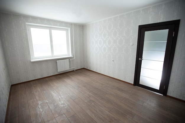 Lege kamer met laminaatvloeren met witte muren en raam