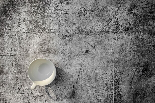 Lege keramische koffiekop op betonnen grunge stijl textuur achtergrond en glinsterende licht bovenaanzicht