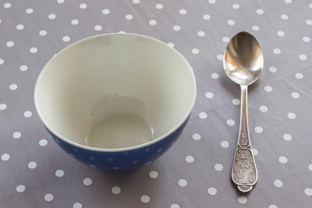 Lege kom en lepel op tafel met grijs polka dot tafelkleed