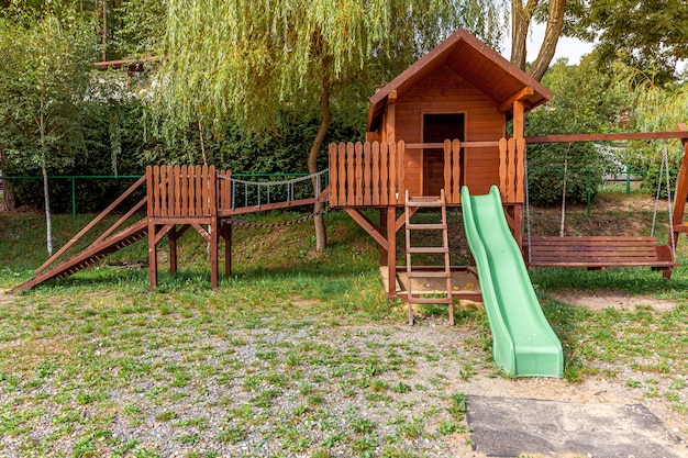 Lege moderne houten kinderspeelplaats ingesteld op groene tuin in openbaar park in zomerdag.