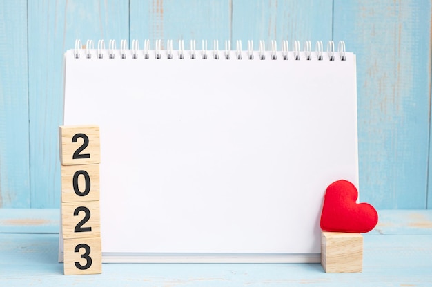 Lege notebook en 2023 kubussen met rode hartvorm decoratie op blauwe houten tafel achtergrond Nieuwjaar NewYou doel resolutie gezondheid liefde en Happy Valentine's day concept