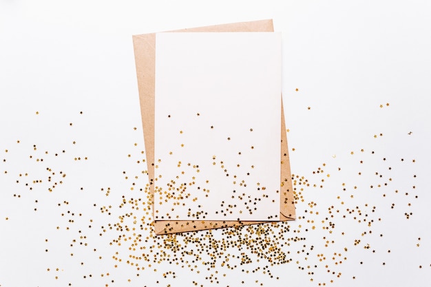 Lege notitie met envelop en gouden glittersterren op wit